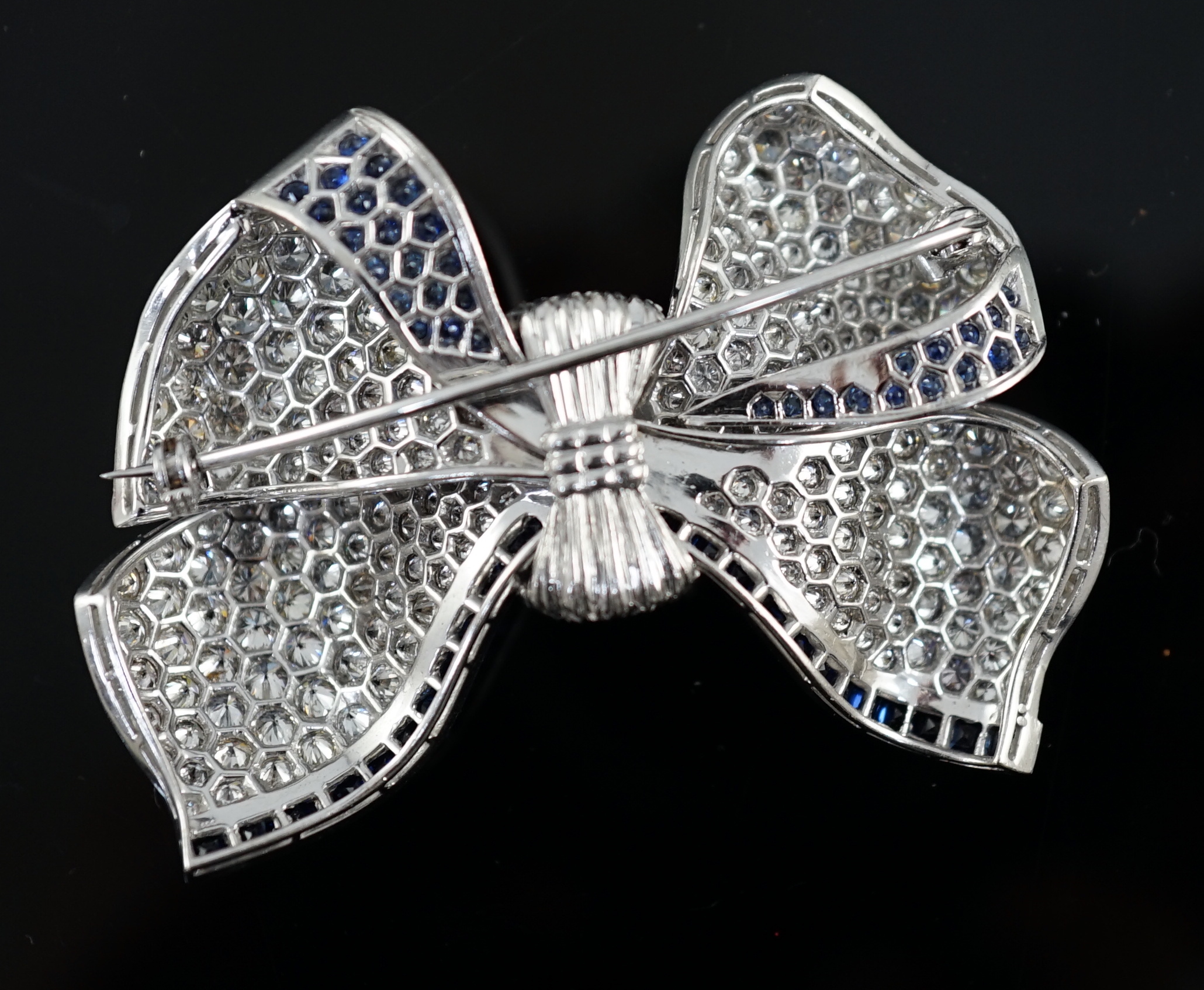 A modern white gold and pave set diamond and sapphire set ribbon bow brooch